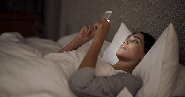 Mujer con un tel�fono en la cama