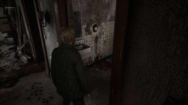 Silent Hill 2 Remake - Calles de Silent Hill: agujero de la pared del baño donde se encuentra el botón de gramola