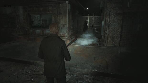Silent Hill 2 Remake - Calles de Silent Hill (Otro Mundo): verja con un agujero junto al Happy Burger