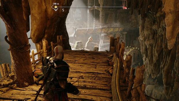 God of War: Ragnarok - En busca de Tyr: Kratos en primer plano, en una plataforma de las minas. Al fondo puede verse una artesa con un mecanismo que permite engancharla con las Espadas del Caos para cambiar el curso del agua