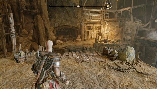 God of War: Ragnarok - En busca de Tyr: Kratos sobre una plataforma de la zona minera. Frente a él hay unas tablas por las que saltar hasta las rocas de al lado, y un muero por el que trepar puede verse al fondo